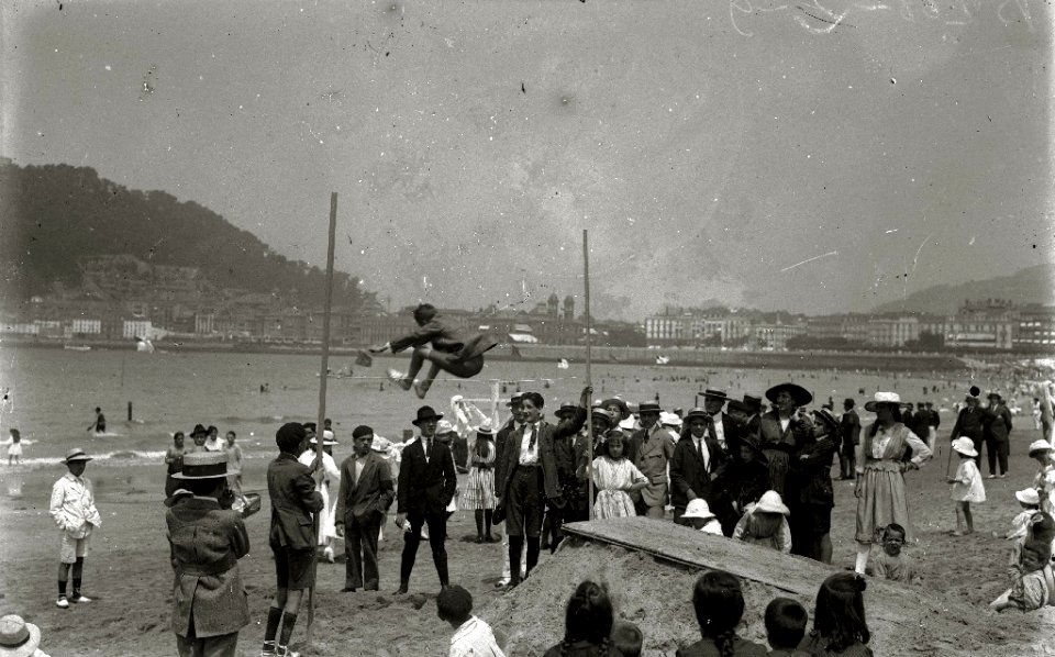 Niños jugando al salto de altura en la playa de la Concha, siendo observados por mayores (1 de 1) - Fondo Car-Kutxa Fototeka