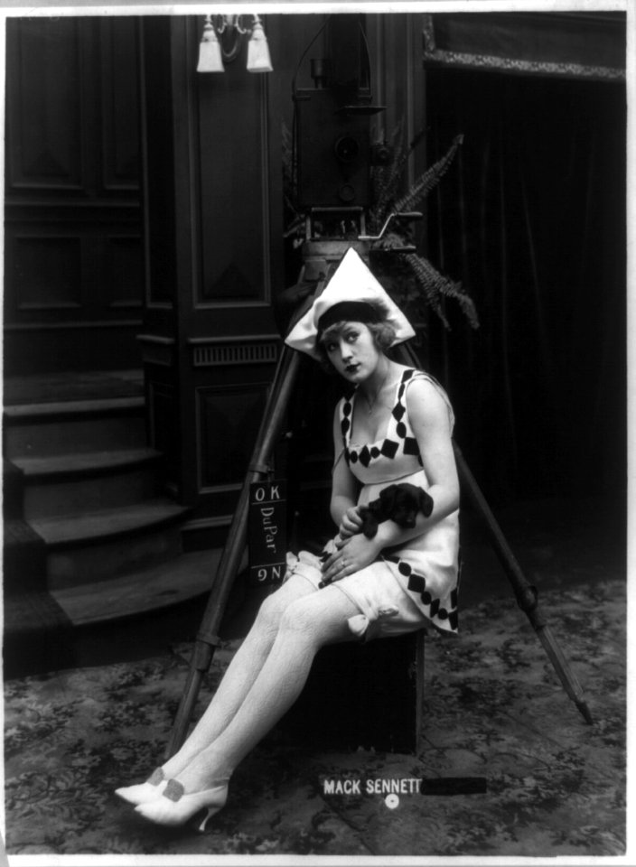 Marvel Rea of Mack Sennett comedy films seated, in front of motion picture camera, full-length portrait, holding puppy LCCN89711792