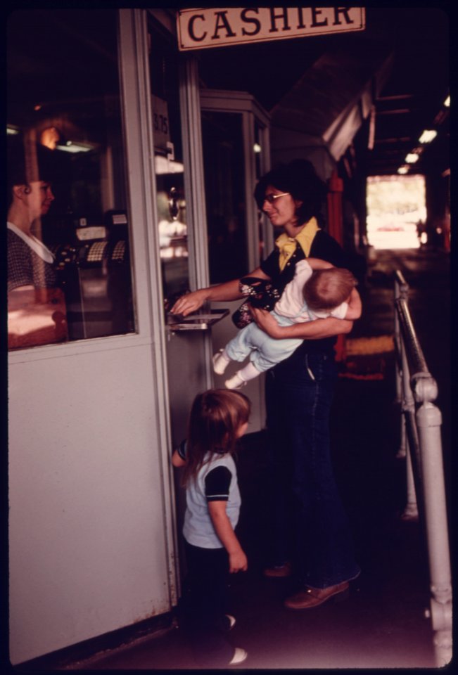 Mother with Her Children at the Cashier's Window Paying for Her Annual Sticker after Her Car Had Successfully Passed Testing at an Auto Emission Inspection Station in Downtown Cincinnati, Ohio...09-1975 (4265798115)