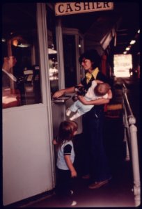 Mother with Her Children at the Cashier's Window Paying for Her Annual Sticker after Her Car Had Successfully Passed Testing at an Auto Emission Inspection Station in Downtown Cincinnati, Ohio...09-1975 (4265798115)
