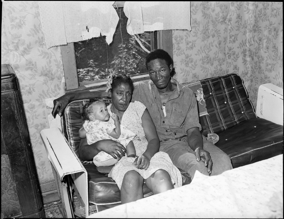 Mr. & Mrs. Tommy Howell with visiting child in living room of their three room house for which they pay $7 monthly.... - NARA - 540714