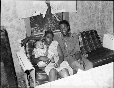 Mr. & Mrs. Tommy Howell with visiting child in living room of their three room house for which they pay $7 monthly.... - NARA - 540714