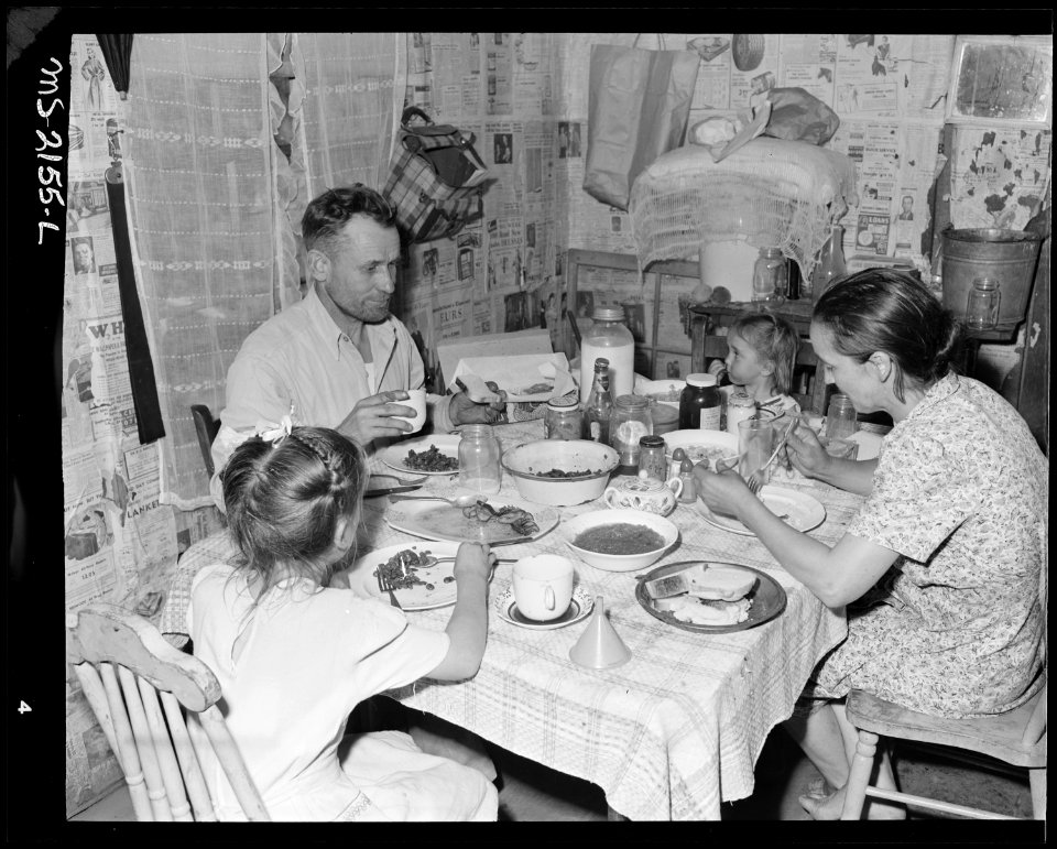 Mr. and Mrs. Charlie Davis and their two children eating dinner in the kitchen of their two room house. Fox Ridge... - NARA - 541144