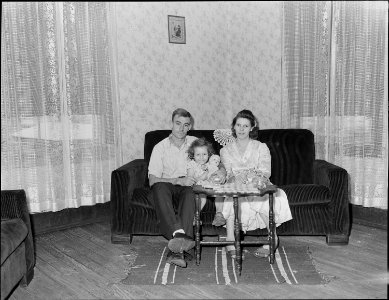 Mr. and Mrs. Lewis Moncy and their daughter in the living room of their home, they have repapered, painted and... - NARA - 541029