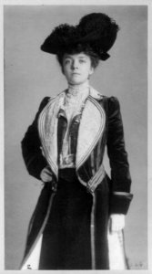 Mrs. Alice Roosevelt Longworth, three-quarter length portrait, standing with right hand on hip, wearing coat and hat LCCN97513656