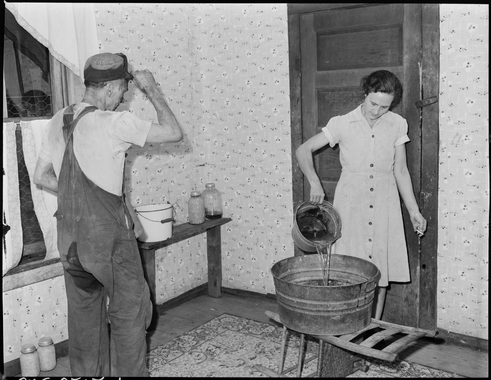 Mrs. Blaine Sergent pours out the bath water for her husband, this company has no bath house, there is no running... - NARA - 541290