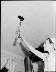Mrs. Blaine Sergent turns on the kitchen light. They pay $2.30 monthly for electriciy which they use for four drops... - NARA - 541330