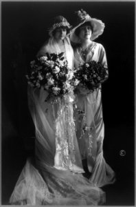 Mrs. Frederick Bourne and sister, full-length portrait, standing, wearing gowns and holding flowers LCCN96524540