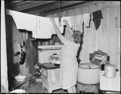 Mrs. Furman Currington, wife of miner, hangs up laundry in kitchen of her 6 room house which rents for $15.00 per... - NARA - 541256 photo