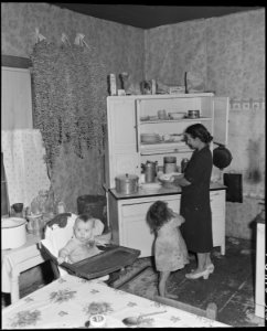 Mrs. George Hoskins, wife of a miner, and two of her ten children in the kitchen of their three room house. Coleman... - NARA - 541132