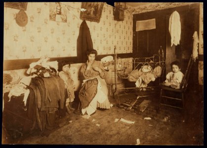 Mrs. Guadina, living in a rear house at 231 Mulberry St. N.Y., a dirty poverty-stricken home, and making a pittance by finishing pants. On the trunk is the work of four days. She was LOC nclc.04144