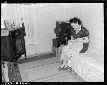 Mrs. Dan Marques, wife of miner, living in company housing project, does some sewing in one of the bedrooms of their... - NARA - 540442