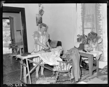 Mrs. Irving Bittick, ironing in living room of her home in company housing project. Independent Coal & Coke Company... - NARA - 540522