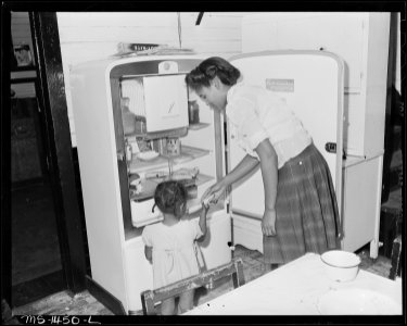 Mrs. James Robert Howard gives her daughter a banana from electrical refrigerator. The Howard bill for electricity is... - NARA - 540800