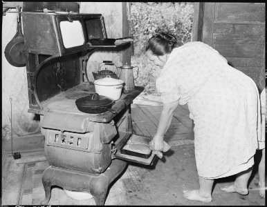 Mrs. Gillie Treadway, wife of a miner, taking freshly baked bread from oven. The Treadways have lived in this camp... - NARA - 541161