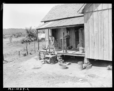 Mrs. Luther Nixon, wife of miner, sweeps the back porch of her farmhouse. Mr. Nixon works at Paul Reese Coal Company... - NARA - 540655