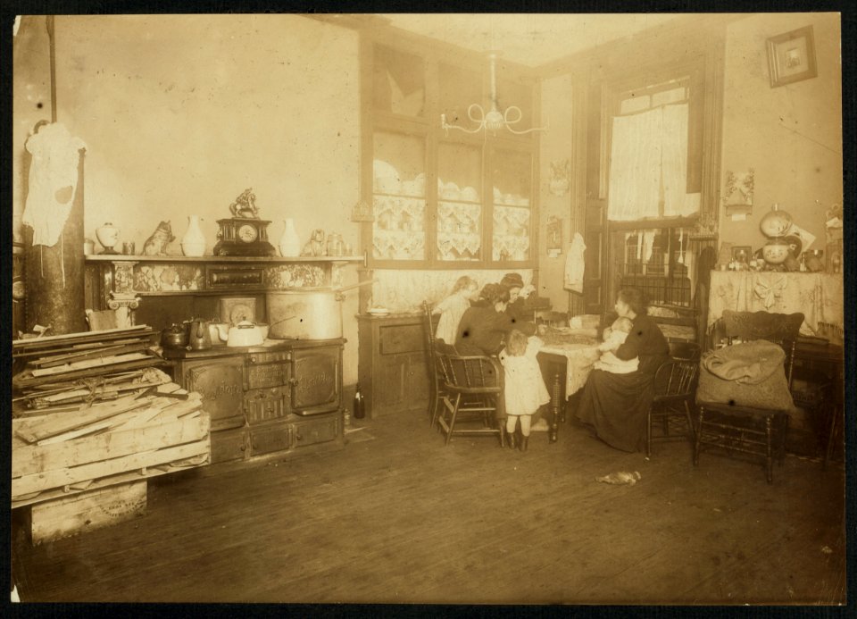 Mrs. Mary Caperale (a widow), 141 Hudson St., picking nuts, while her two daughters help her. The dirty children are handling the nuts and playing with them. The open bag of nuts stands LOC nclc.04094