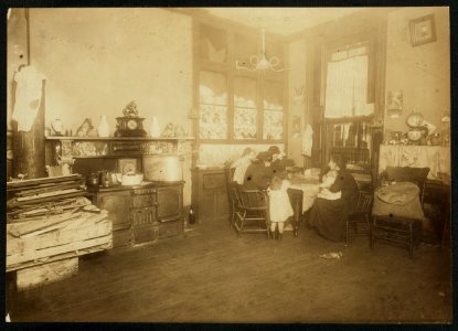 Mrs. Mary Caperale (a widow), 141 Hudson St., picking nuts, while her two daughters help her. The dirty children are handling the nuts and playing with them. The open bag of nuts stands LOC nclc.04094
