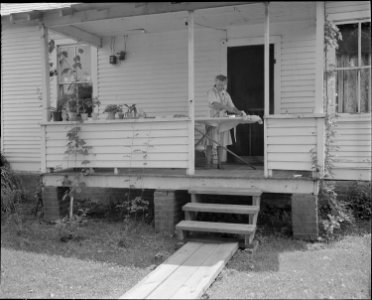 Mrs. Oswald Baldwin, wife of mine mechanic, ironing on her front porch. She and her husband have lived in this four... - NARA - 540979