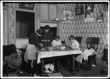 Mrs. Salvia, Joe, 10 years old, Josephine, 14 years, Camille, 7 years, picking nuts in a dirty tenement home. The bag... - NARA - 523490 photo
