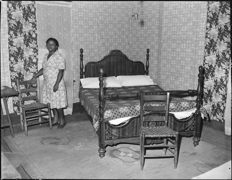 Mrs. Robert Harold in the bedroom of her house. Her husband, a miner, has lived in this house for sixteen years. For... - NARA - 541054