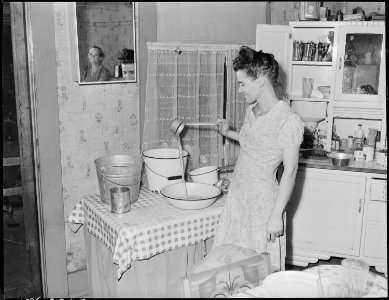 Mrs. Robert Moffett, with of miner, in her kitchen. They have lived in this house for 2 years, rental $10.00 per... - NARA - 541260