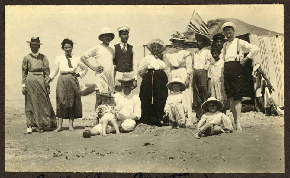 Mrs. Weston, standing in center, and friends at the beach in Jaffa with an American flag waving in background LCCN2007682806
