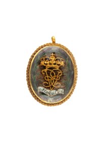 Medaljong med cendréfärgat hår över vilket är fäst krönt spegelmonogram av guld, U E - Livrustkammaren - 97852