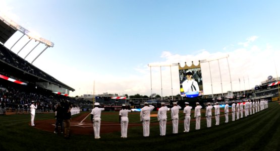 Musician 3rd Class Leigh Donaldson sings the national anthem as Sailors line the bases at the Kansas City Royals Navy Day baseball game