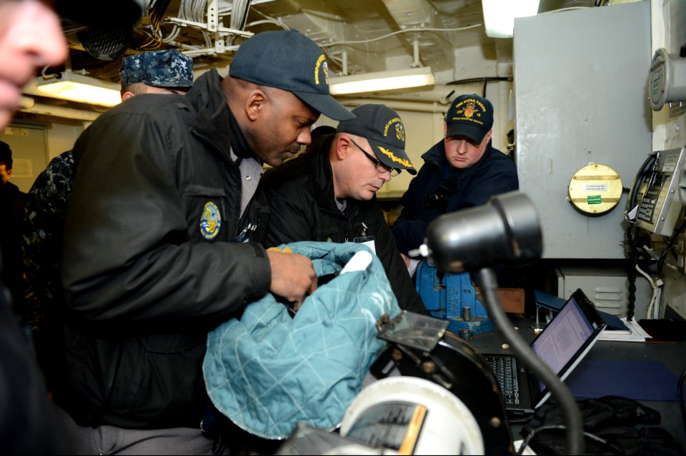 Members of a U.S. Navy Board of Inspection and Survey (INSURV) verify the proper labeling of a crash and salvage helmet aboard the amphibious transport dock ship USS Mesa Verde (LPD 19) Jan. 16, 2014, in 140116-N-BD629-040