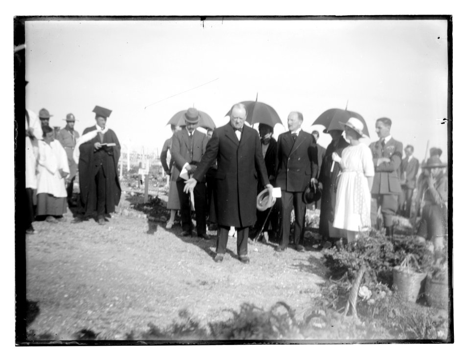 Men and women, including possibly Winston Churchill and Herbert Samuel, in a military cemetery with Christian clergy LOC matpc.11629
