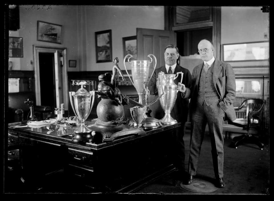 Men with trophy cups on desk LCCN2016887004