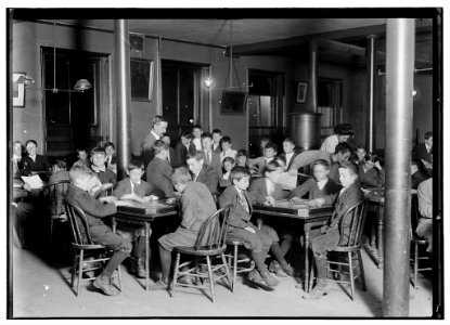 Name- In the Newsboys Reading Room. Boys seated at tables playing gamers. Boston 1915 Exhibit. Oct. 1909. LOC nclc.05433