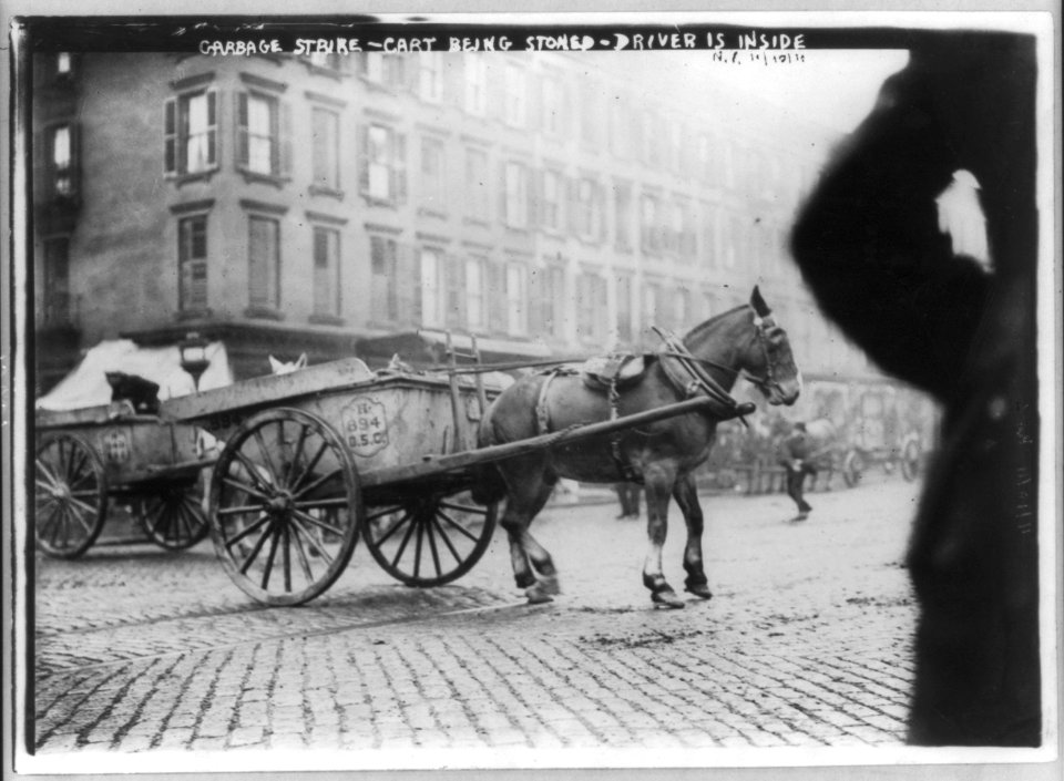 N.Y.C. Garbage collector's strike, 1911- horse-drawn cart being stoned; driver is hiding inside LCCN2007678131