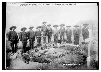 Mexican rurales, dead insurrectos, and body of Edw. Lawton lying in pit, with surrounding guard LCCN2014688852
