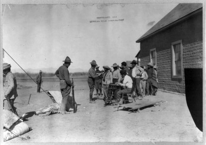 Mexican War, 1914- U.S. soldiers interviewing Mexican refugees; man wearing bowler hat and Red Cross armband seated in center LCCN2003655558