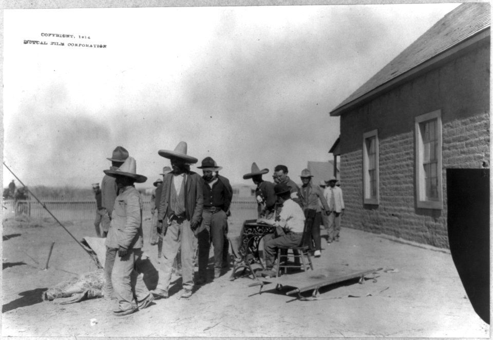 Mexican War, 1914- U.S. soldiers interviewing Mexican refugees; man wearing bowler hat and Red Cross armband seated in center LCCN2003655559