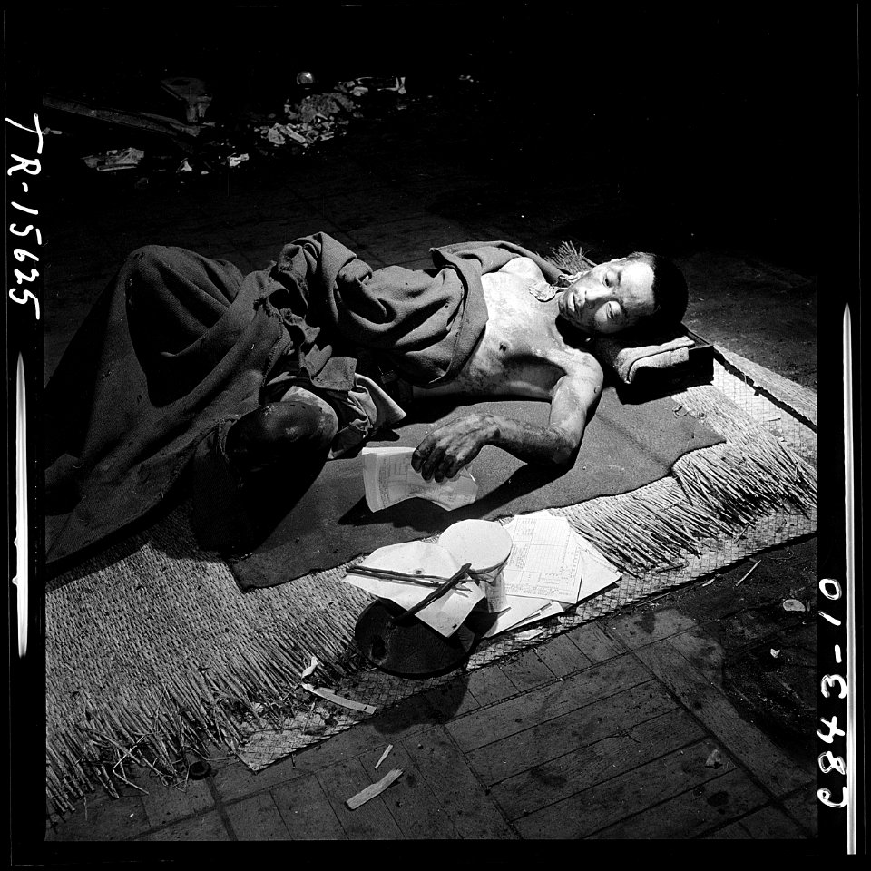 Navy photographer pictures suffering and ruins that resulted from atom bomb blast in Hiroshima, Japan. Victim lies in... - NARA - 520933