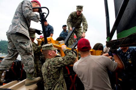 Navy Seabees and Air Force RED HORSE engineers unload a ship during Pacific Partnership 150628-N-UQ938-017