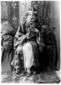 Neith Boyce Hapgood,full-length portrait, seated facing front, wearing ornamental costume and holding roses LCCN91789198