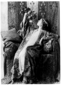 Neith Boyce Hapgood,full-length portrait, seated, left profile, wearing ornamental costume and holding up roses LCCN91789199