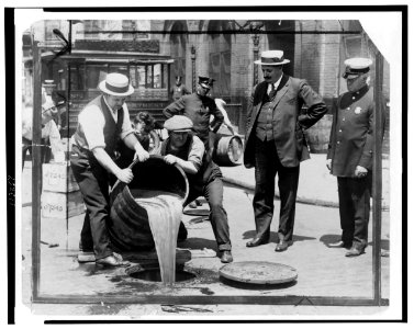 New York City Deputy Police Commissioner John A. Leach, right, watching agents pour liquor into sewer following a raid during the height of prohibition LCCN99405169
