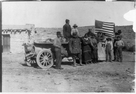 New York to Paris auto race, 1908- drivers and Indians holding U.S. flag posed by auto in front of house LCCN2004679576