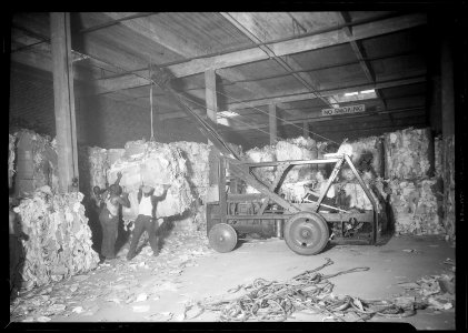 New York, New York - Longshoremen. A tractor crane is loading bales of scrap paper from warehouse of the Bush... - NARA - 518786 photo