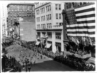 News photos of N.Y. National Guard units preparing for active duty on Mexican border, May-Nov. 1916- Departure of 7th Regiment, parading down 5th Avenue, passing gigantic U.S. flag LCCN2005691551