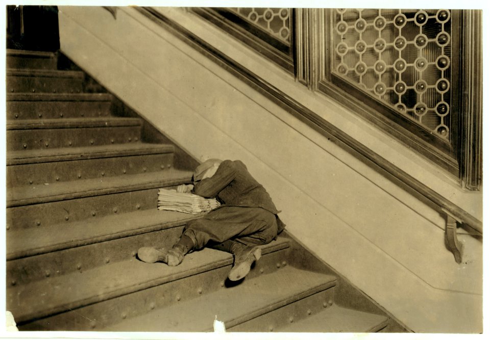 Newsboy asleep on stairs with papers. LOC cph.3a26047