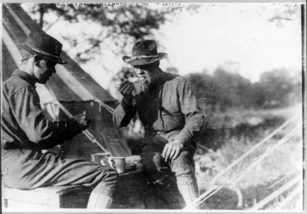 News photos of N.Y. National Guard units preparing for active duty on Mexican border, May-Nov. 1916- 2 soldiers eating outside tent at Van Cortlandt Park LCCN2005691552