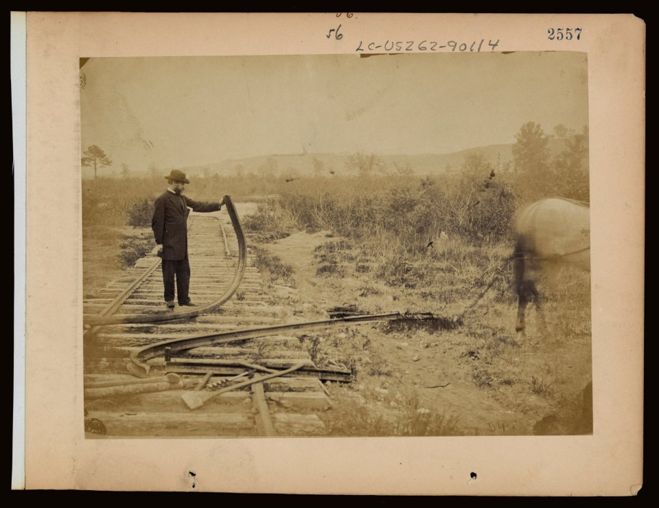 Military railroad operations in northern Virginia- man standing on railroad tracks holding twisted rail LCCN97502059