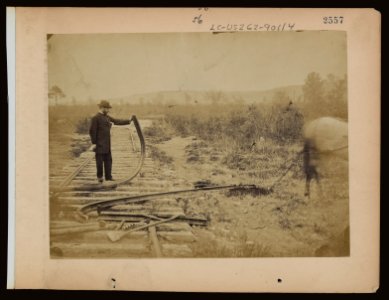 Military railroad operations in northern Virginia- man standing on railroad tracks holding twisted rail LCCN97502059