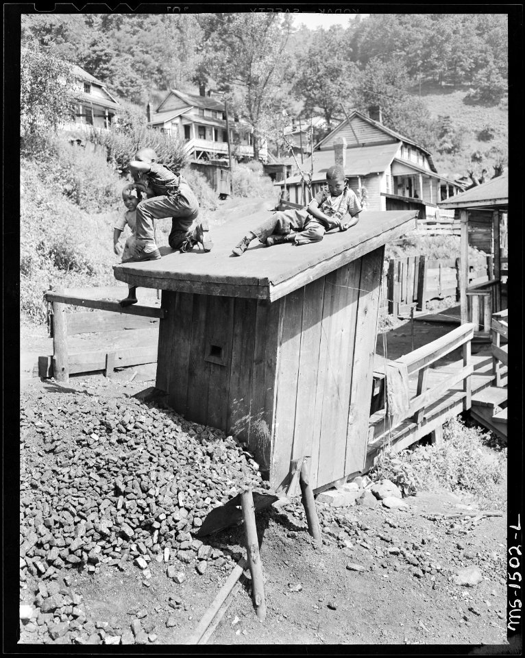 Miner's children play on top of the Howard family privy. There is no place for children to play in this camp other... - NARA - 540824